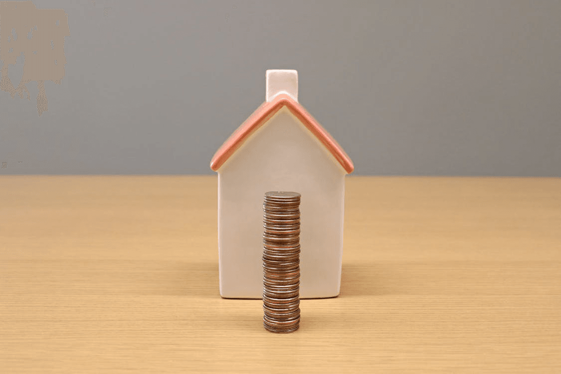 A large house with a money stack in front of it