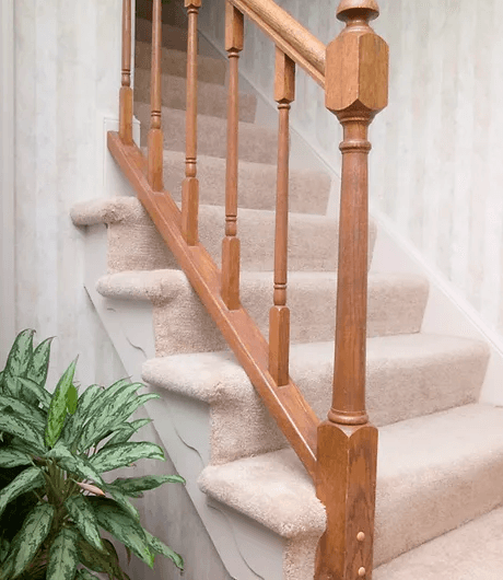 Carpeted stairs with a wooden railing on the side