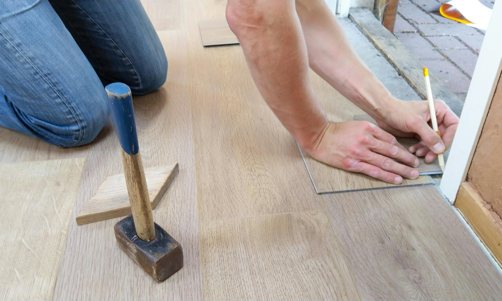 a person measuring the corner of a wall to install new flooring