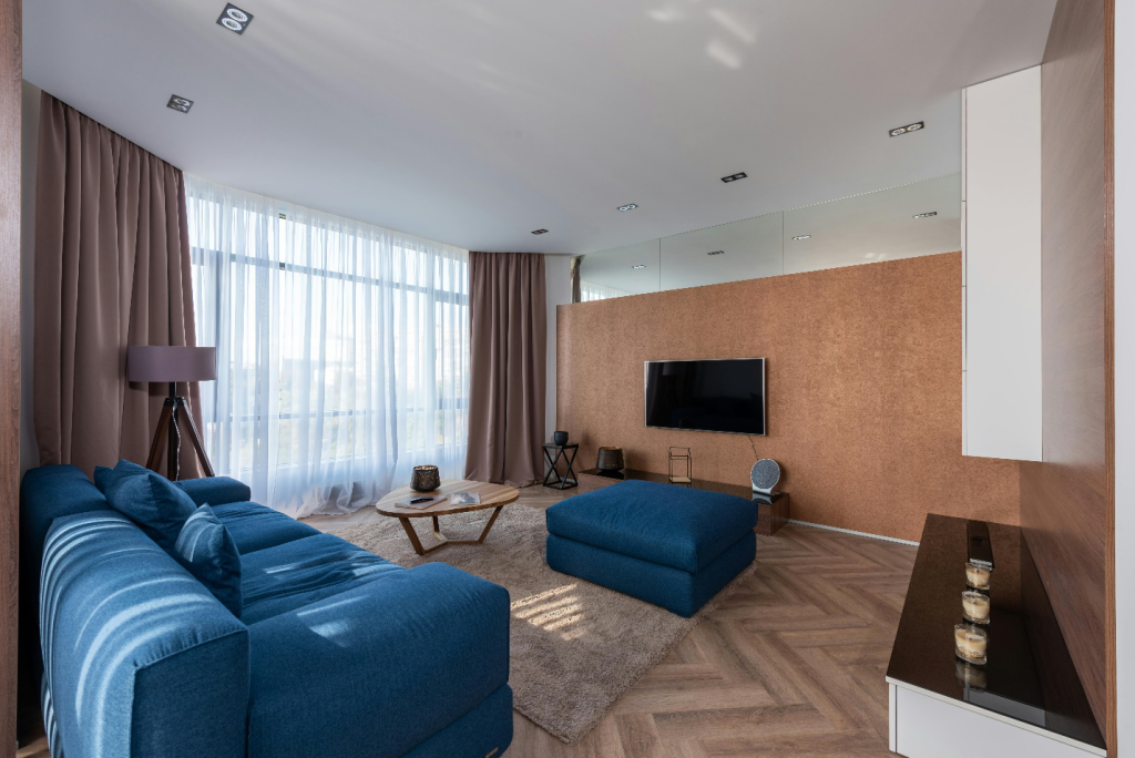 a small living room with a big blue sofa set and wall-mounted TV