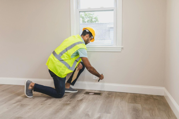 Contractor inspecting living room flooring for quality and precision.